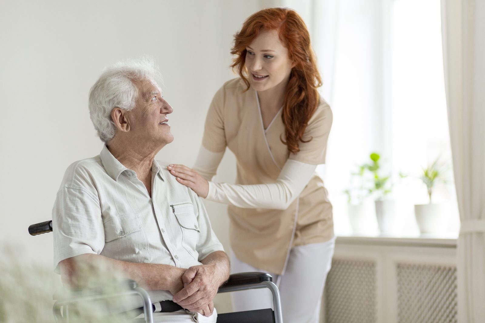 Caregiver supporting an older adult outdoors in a wheelchair